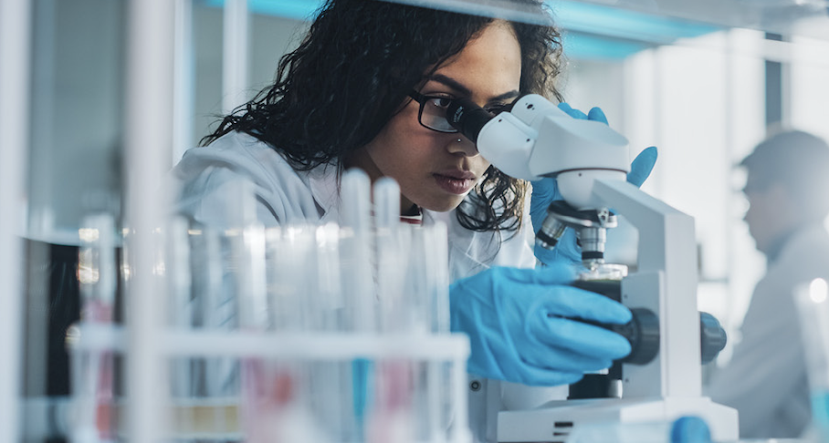 researcher looks into microscope